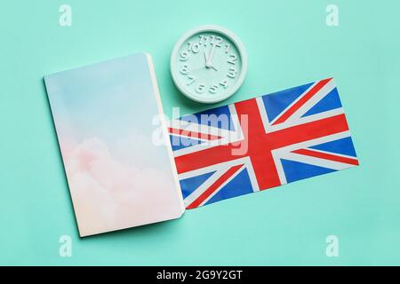 Notizbuch, Uhr und UK-Flagge auf farbigem Hintergrund. Zeit, Englisch zu lernen Stockfoto
