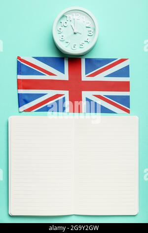 Notizbuch, Uhr und UK-Flagge auf farbigem Hintergrund. Zeit, Englisch zu lernen Stockfoto