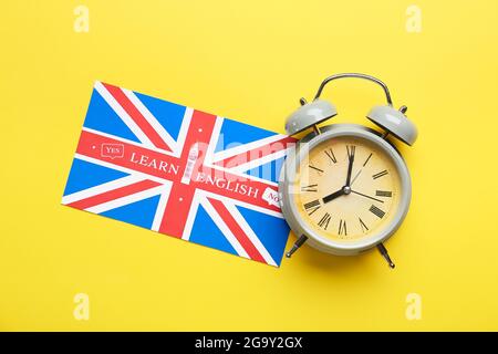 Uhr und UK-Flagge auf farbigem Hintergrund. Zeit, Englisch zu lernen Stockfoto