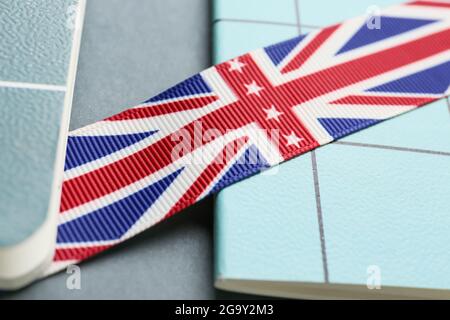 Notizbücher und Band in den Farben der britischen Flagge auf grauem Hintergrund, Nahaufnahme. Konzept des Englischlernens Stockfoto