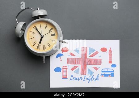 Uhr und Zeichnung der britischen Flagge auf grauem Hintergrund. Zeit, Englisch zu lernen Stockfoto