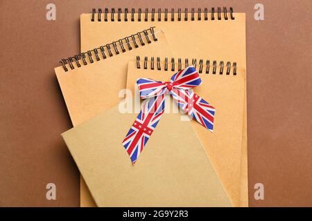 Notizbücher und Band in den Farben der britischen Flagge auf dem farbigen Hintergrund. Konzept des Englischlernens Stockfoto