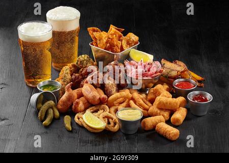 Bierset mit herzhaften Snacks mit Saucen, Gurken und Zitrone Stockfoto