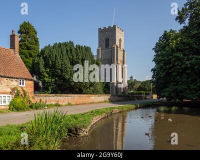 Idyllische englische Dorfszene im Sommer, Blick über einen Ententeich zu einer Kirche mit einem alten Häuschen im Vordergrund; Old Hunstanton, Norfolk, UK Stockfoto