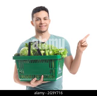 Junger Mann mit frischem Gemüse, der auf etwas auf weißem Hintergrund zeigt Stockfoto