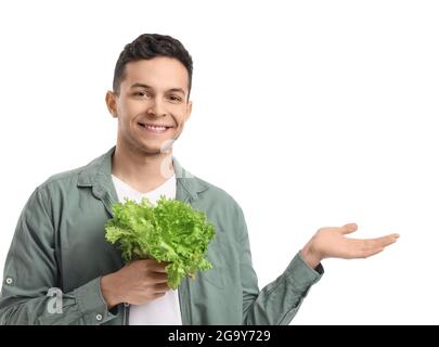 Junger Mann mit frischem Salat, der etwas auf weißem Hintergrund zeigt Stockfoto