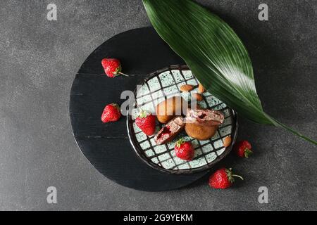 Teller mit leckeren japanischen Mochi und Erdbeere auf dunklem Hintergrund Stockfoto