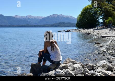 Mädchen sitzt auf Felsen am Nahuel Huapi See, Patagonien, Argentinien Stockfoto