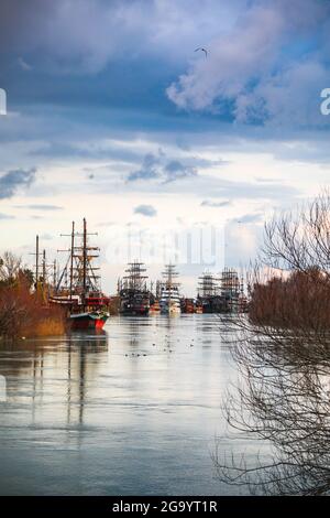 Blick auf Piratenschiffe vor Anker am Sunset in River Manavgat mit purpurner Wolke und Baumspiegelung. Stockfoto