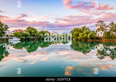 Sonnenuntergang im Fluss Manavgat mit purpurner Wolke und Baumspiegelung. Stockfoto