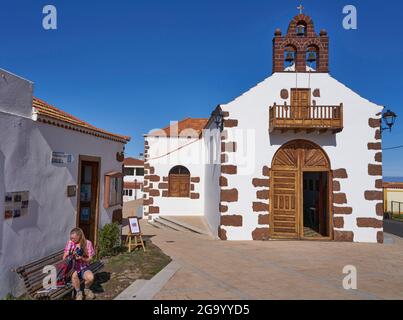 Eine Wanderin, die eine Pause auf dem Platz vor der Kirche De Nuestra Senora de Carmen, Kanarische Inseln, La Palma, Las Tricias macht Stockfoto