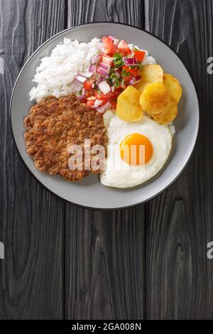 Silpancho ist ein beliebtes bolivianisches Essen und besteht aus einer Grundschicht aus Reis, Kartoffelscheiben, gebratenem Fleisch, Ei in der Nähe auf dem Teller auf dem Tisch. Stockfoto