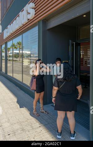 Mallorca, Spanien, 07-27-2021. MacDonald Logo, Familie beim Betreten von Macdonalds Fast-Food-Restaurant, indem sie eine Maske aufsetzt, um eine Ansteckung von Covid-19 zu vermeiden Stockfoto