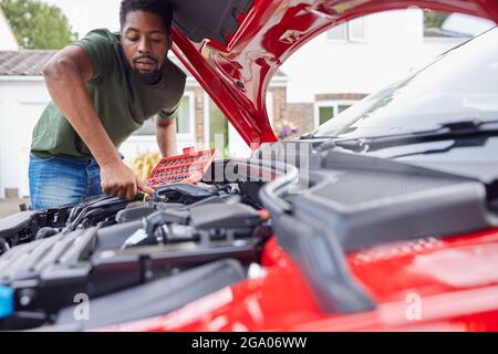 Mann, Der Unter Der Haube Des Auto-Befestigungsmotors Mit Dem Schraubenschlüssel Arbeitet Stockfoto