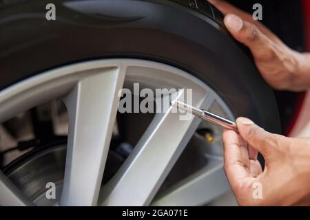 Nahaufnahme des Mannes Auto Reifendruck mit Manometer überprüfen Stockfoto