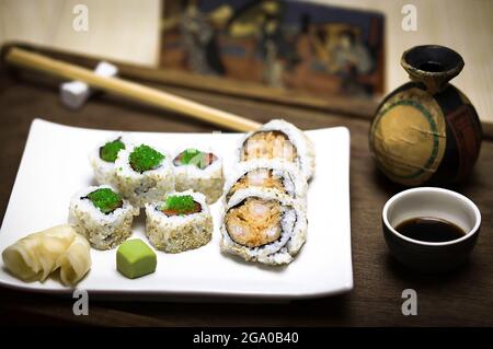 Ein eleganter weißer Teller mit frischem, gesundem Gourmet-Maki-Sushi in Scheiben geschnittene Rollen aus Reis, rohem Lachs und Thunfisch, grünem Kaviar, Garnelen und Nori Stockfoto