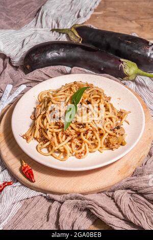 Traditionelle sizilianische Pasta-Gericht aus sautierten Auberginen mit Tomatensauce gekrönt. Das Essen wird auf einem Keramikplatte serviert, italienische Küche, modernes hartes Licht, dunkel Stockfoto