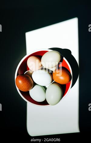 Ansicht von oben auf eine Gruppe von Eiern in einer roten Schüssel in rauem Licht Stockfoto