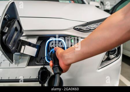 Junger Mann lädt sein umweltfreundliches Elektrofahrzeug Stockfoto