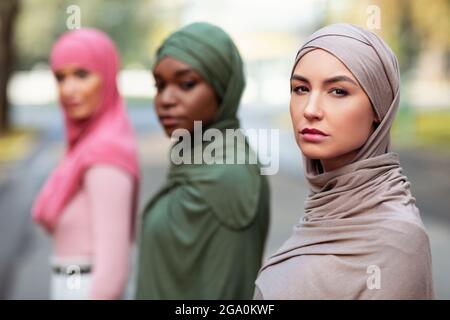 Drei Ernsthafte Junge Muslimische Damen Posieren Beim Blick Auf Die Kamera Im Freien Stockfoto