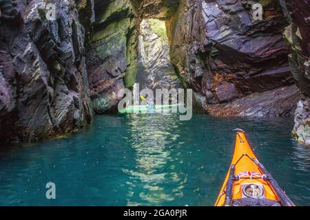 Erkunden Sie Meereshöhlen, während Sie vor der Küste von Anglesey, Nordwales, Großbritannien, Kajakfahren Stockfoto