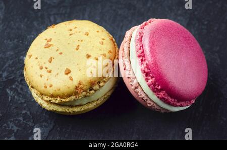 Zwei süße französische Macarons auf dunklem Grund. Stockfoto