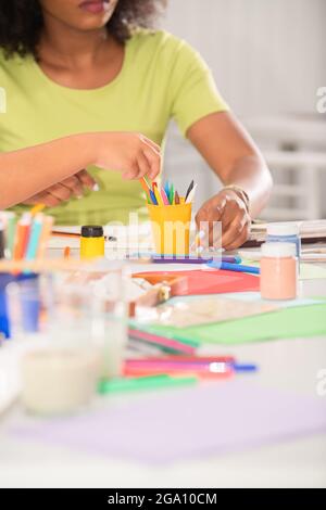 Nahaufnahme eines Lehrers beim Zeichnen im Kunstunterricht und der verschiedenen Buntstifte und Schulmaterialien auf dem Tisch Stockfoto