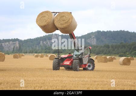 Blankenburg, Deutschland. Juli 2021. Strohballen werden auf einem Feld im Vorland des Harzes beladen. Der Regenstein ist im Hintergrund zu sehen. Quelle: Matthias Bein/dpa-Zentralbild/ZB/dpa/Alamy Live News Stockfoto