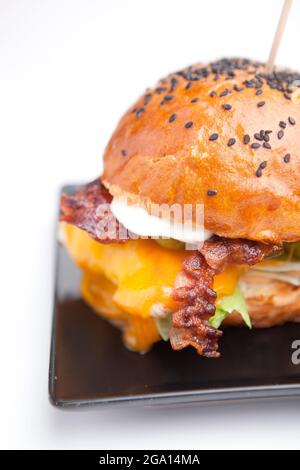 Cheeseburger mit Speck, Salat und Chips. Kalorienreiche Lebensmittel. Geschmolzener, fester, glatter Cheddar-Käse, ursprünglich hergestellt in Cheddar im Südwesten Englands. Stockfoto