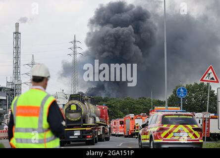 Leverkusen, Deutschland. Juli 2021. Nicht weit von einer Zufahrtsstraße zum Chempark, über der eine dunkle Rauchwolke aufsteigt, stehen Einsatzfahrzeuge der Feuerwehr. Quelle: Oliver Berg/dpa/Alamy Live News Stockfoto