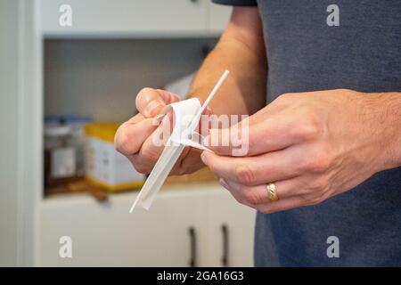 COVID-19 PCR-Heimtestkits werden immer prominenter und erschwinglicher, wie dieser Mann zeigt, der einen Test in seinem Haus abnimmt. Stockfoto