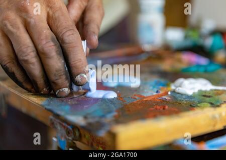 Nahaufnahme von Hand Mischfarbe auf Palette in der Werkstatt Stockfoto