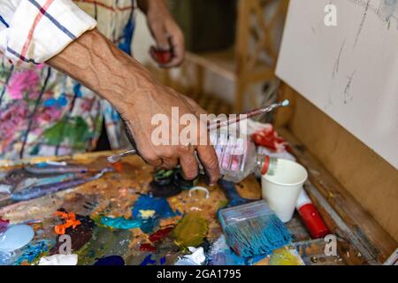 Nahaufnahme von Hand Mischfarbe auf Palette in der Werkstatt Stockfoto