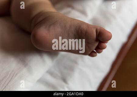 Füße von Kleinkind Baby Mädchen tragen Windeln liegen auf weißem Bett zu Hause. Plump Beine schlafen ein Jahr altes kaukasisches Kind. Kind schläft in der Krippe. Zuhause Stockfoto