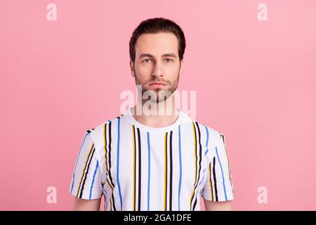 Foto von jungen ernsthaften jungen Mann tragen weiß gestreiften casual T-Shirt isoliert auf rosa Hintergrund Stockfoto