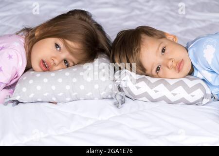 Zuhause, Komfort, Kindheit, Schlaflosigkeit, Schlaflosigkeit, Sweet Dream - zwei traurige müde Kleinkind Geschwister Kinder Kinder Zwillinge in Pyjamas liegen Rest kann nicht schlafen Stockfoto