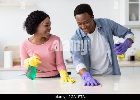 Fröhliches schwarzes Paar, das Küche putzt und Spaß hat Stockfoto