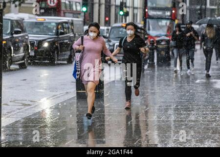 London, Großbritannien. 28 2021. Juli: Heftige Regenschauer treffen Knightsbridge, Central London, England, Großbritannien das Bild zeigt Touristen, die im Regen um Deckung laufen, während starke Regenschauer über das Zentrum Londons und den Süden Englands ziehen. Kredit: Clickpics/Alamy Live Nachrichten Stockfoto