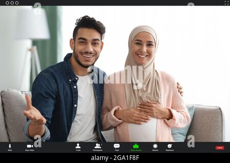 Fröhliche, schwanger-islamische Ehegatten, die von zu Hause aus einen Videoanruf tätigen, POV Screenshot Stockfoto