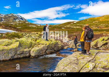 Viken Norwegen 09. Juni 2016 Menschen Wanderer überqueren im Sommer in Hemsedal Norwegen den Fluss an der Landschaft des Vavatn-Sees und der Berge. Stockfoto