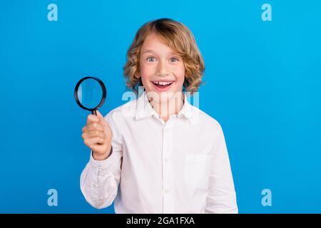 Portrait von attraktiven fröhlichen Jungen halten Lupenglas Experiment isoliert über hellen blauen Hintergrund Stockfoto