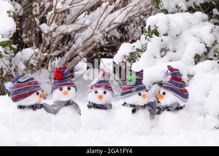 Kleine Schneemänner unterhalten sich mit Hüten und Schals im Schnee während der Wintersaison in Norfolk England Stockfoto