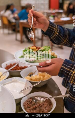 Junge Frau wählt Salat am Buffet des Hotels Stockfoto