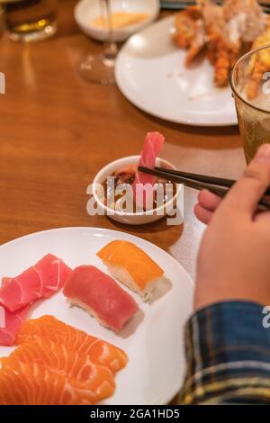 Frau frisst Sashimi mit Essstäbchen Stockfoto