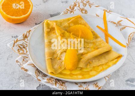 Crepe Suzette, französischer dünner Pfannkuchen mit Orangensauce und Früchten, auf weißem Hintergrund Stockfoto