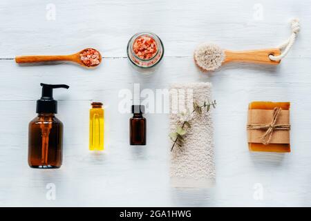 Badaccessoires und Naturkosmetik, himalaya-Rosa-Salz im Glas, ätherische Öle auf weißem Holztisch. Zero Waste Konzept. Draufsicht, flach liegend Stockfoto