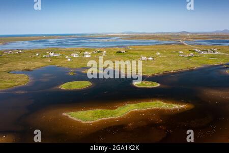 Luftaufnahme von der Drohne des Dorfes Geirinis und der Ruine von Dun Mor Broch auf der Insel in South Uist, Äußere Hebriden, Schottland, Großbritannien Stockfoto