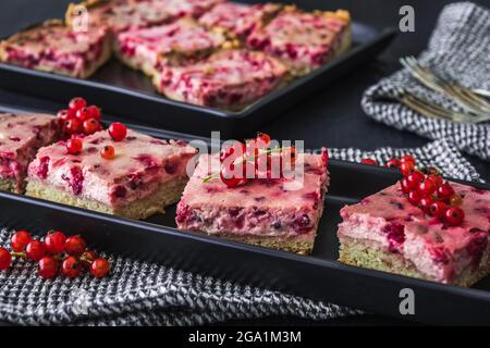 Stücke von cremig roten Johannisbeerkuchen auf einem schwarzen Teller Stockfoto