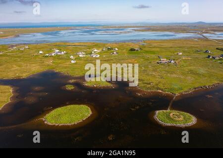 Luftaufnahme von der Drohne des Dorfes Geirinis und der Ruine von Dun Mor Broch auf der Insel in South Uist, Äußere Hebriden, Schottland, Großbritannien Stockfoto