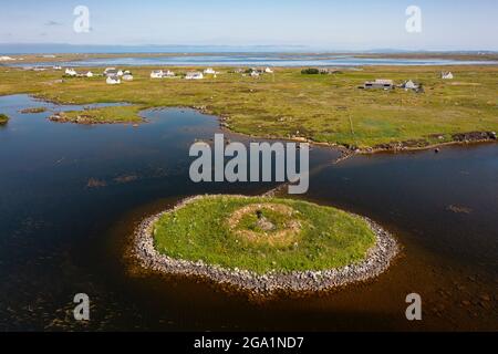 Luftaufnahme von Drohne des Dorfes Geirinis und Ruine von Dun Mor Broch auf Crannog in South Uist, Äußere Hebriden, Schottland, Großbritannien Stockfoto